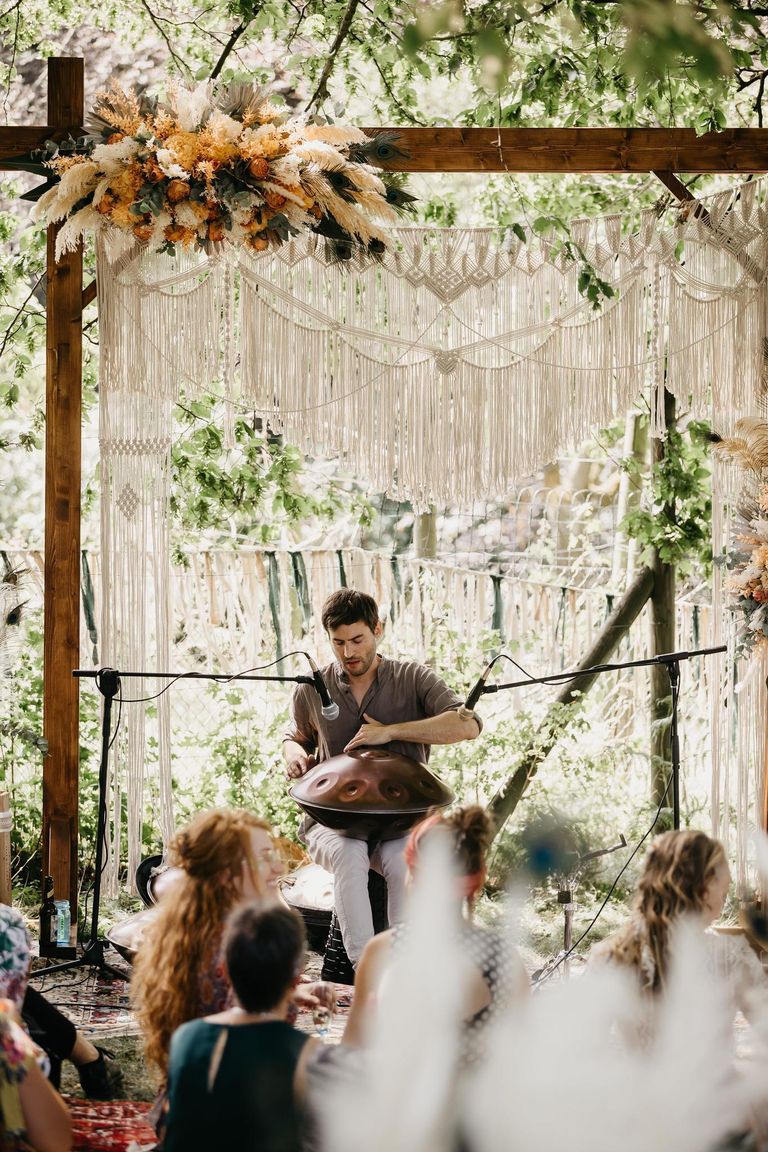Lorenz Schmidt spielt Handpan bei einer Hochzeit im Freien, umgeben von Grün und Gästen