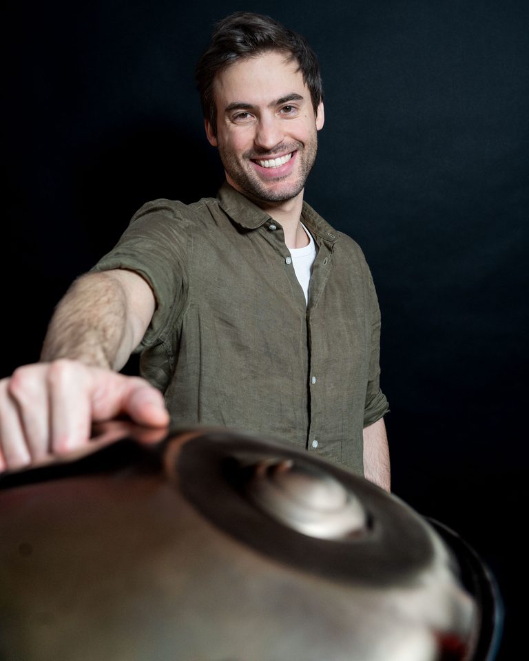 Lorenz Schmidt lachend hinter einer Handpan vor dunklem Hintergrund
