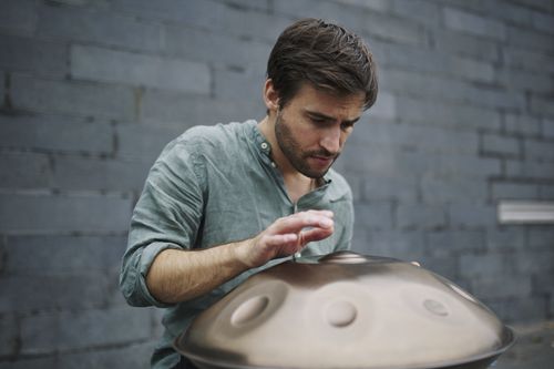 Lorenz Schmidt spielt Handpan vor einer Ziegelwand